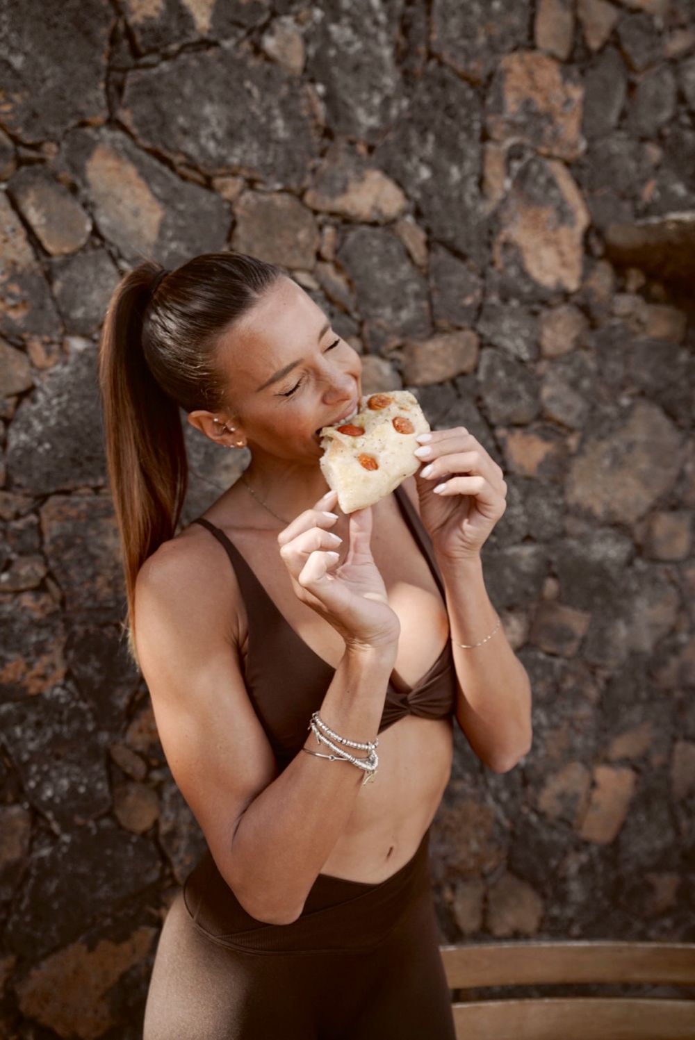Giulia Calcaterra in tenuta da allenamento morde una fetta di focaccia